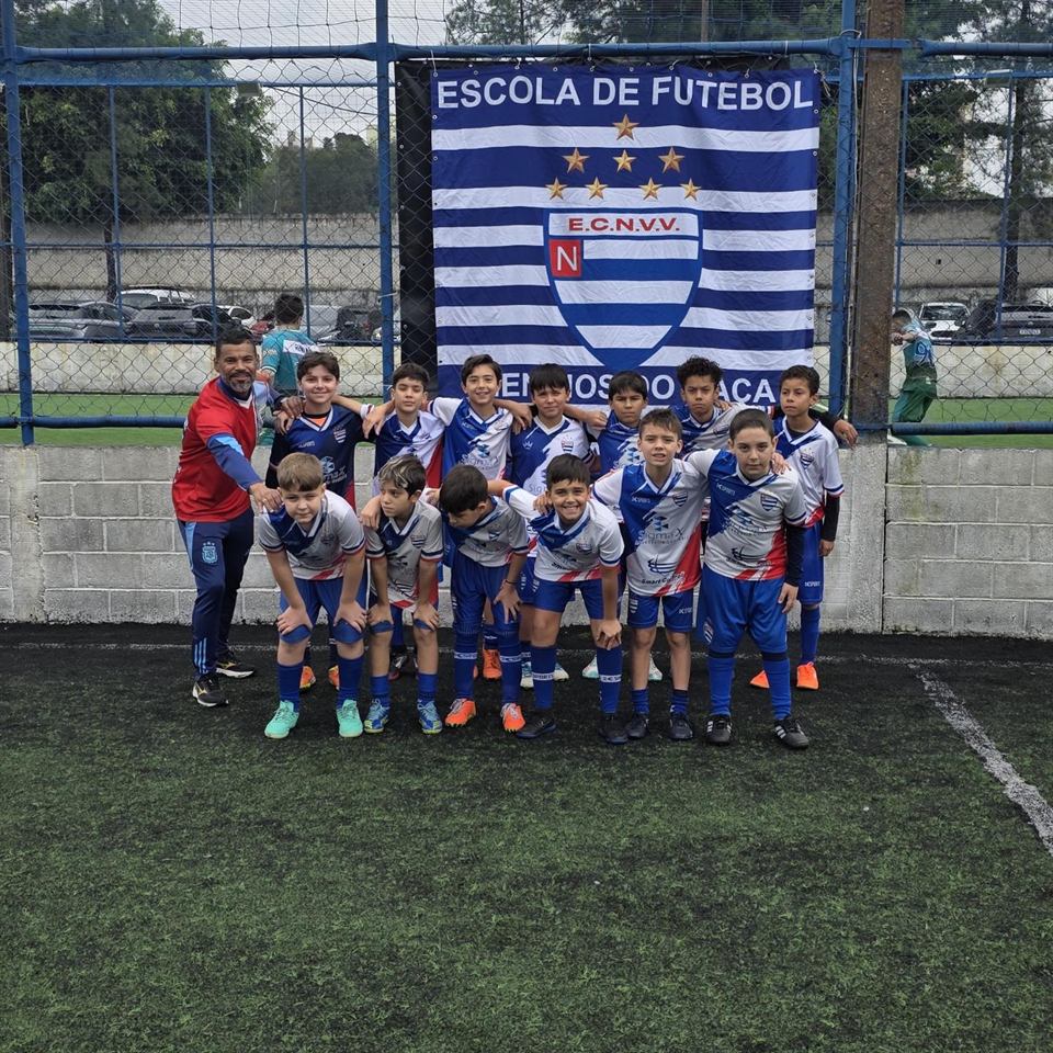 Time do Nacional posado com o professor em frente à faixa Meninos do Naça